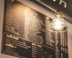 A wire frame with lightbulb with blurry menu board in the background